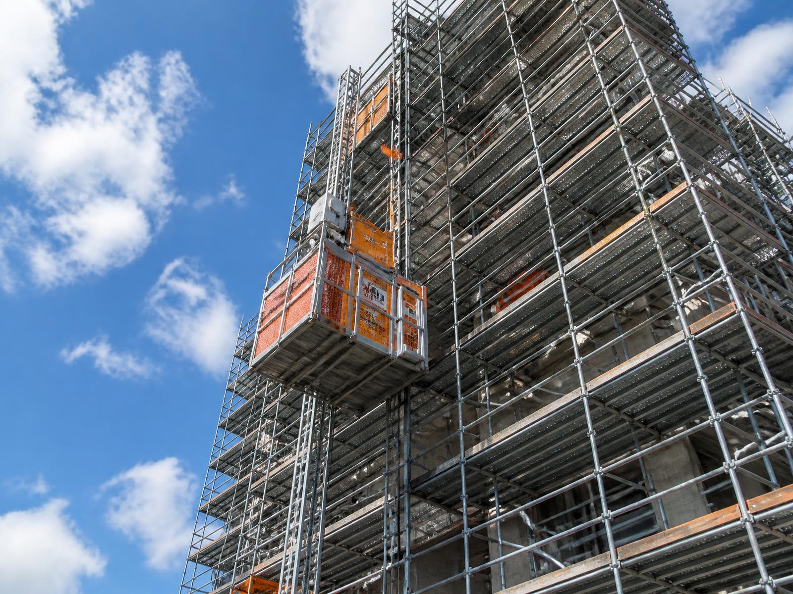 Steigerbouw met bouwlift tegen een blauwe lucht